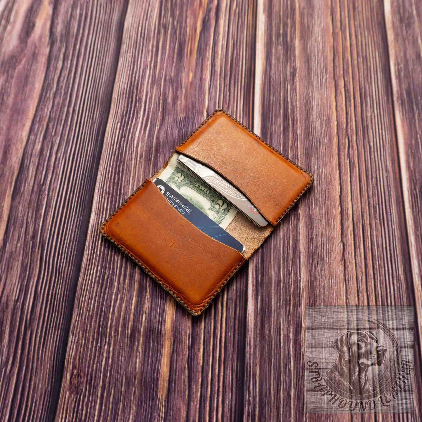 photo of wood grain background with a walnut leather wallet shown open with credit cards and cash